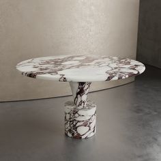 a marble table sitting on top of a metal floor next to a white and brown wall