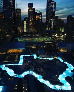 an aerial view of a city at night with blue lights on the water and buildings in the background