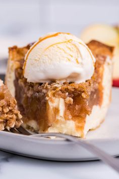 a piece of pie on a plate with ice cream and an apple in the background