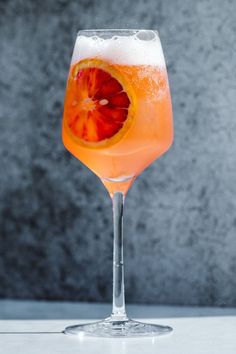 an orange slice in a wine glass filled with liquid