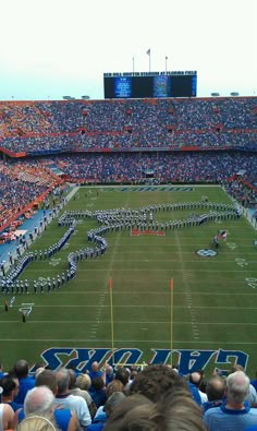 a football stadium filled with lots of people watching the band on the field and marching