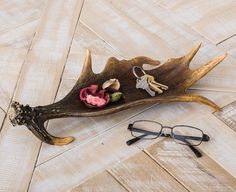 a pair of glasses sitting on top of a piece of driftwood with flowers and keys