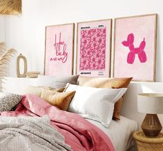 a bedroom with pink and white decor on the wall above the bed is decorated with art