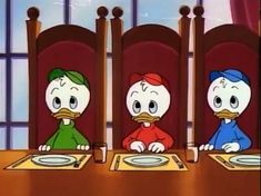 three cartoon characters sitting at a table with plates in front of them, one ducky and the other ducky