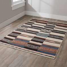 an area rug in the corner of a room with wood flooring and white walls