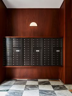 an empty room with many mailboxes on the wall and checkerboard floor