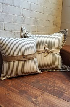 two striped pillows tied together on a wooden bench