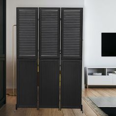 a living room with black shutters and a television on the wall in front of it