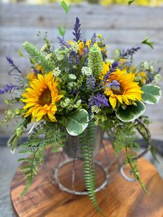 a metal vase filled with yellow and purple flowers