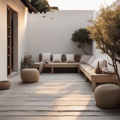 an outdoor living area with couches, tables and potted trees