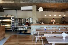 an empty restaurant with tables and chairs in front of the counter, people working behind the counter