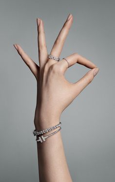 a woman's hand with two bracelets on her wrist and the middle finger in the air