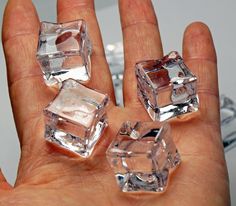 three clear cubes sitting in the palm of someone's hand, with one being held up