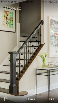 an image of a staircase and table in the living room with pictures on the wall