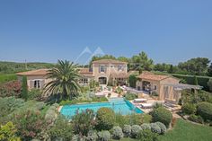 an aerial view of a house with a swimming pool in the foreground, surrounded by greenery and trees