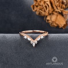 a rose shaped diamond ring sitting on top of a piece of cloth next to a flower