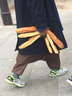 a man is walking down the street carrying breadsticks