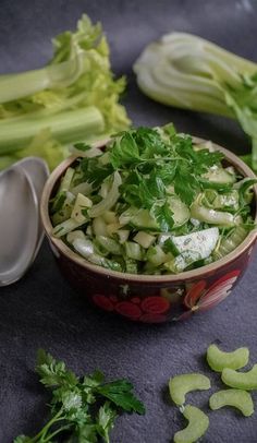 a bowl filled with celery sitting next to some spoons and other vegetables