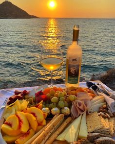 a glass of wine sitting next to a platter of cheeses and crackers