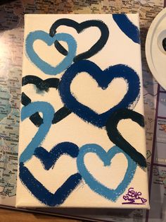 a painting with blue and black hearts painted on it next to a toilet paper roll