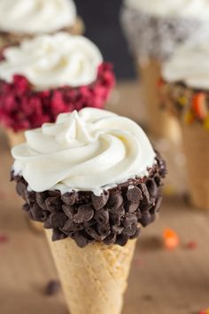 three ice cream cones with white frosting and chocolate chips in them on a table