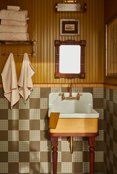 a bathroom sink sitting under a mirror next to a wooden shelf with towels on it