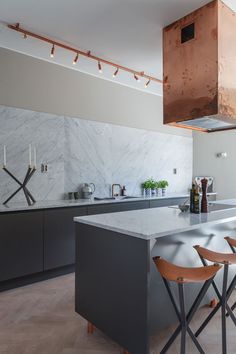 a modern kitchen with marble counter tops and bar stools