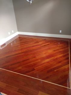 an empty room with hard wood flooring and a chandelier