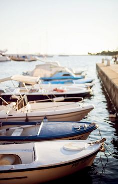 there are many small boats docked in the water near each other and one is white