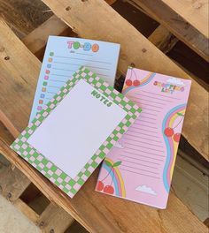 three notepads sitting next to each other on a wooden bench with writing paper