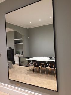 a mirror reflecting a table and chairs in a room with hard wood floors on the floor