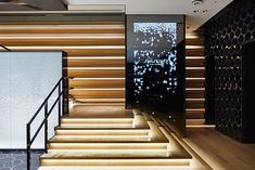 the stairs are lit up with leds in this modern office building, which also features wood paneling and black walls