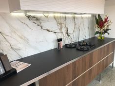 a kitchen with marble counter tops and wooden cabinets, along with a vase filled with flowers