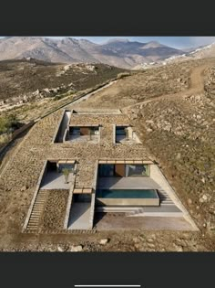 an aerial view of a house in the desert with mountains in the backgroud