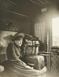 an old black and white photo of a woman sitting on a bed in a room