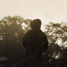 the silhouette of a person standing in front of trees