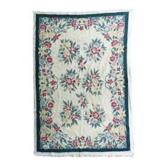 an old quilt with flowers and leaves on the front, hanging from a white wall