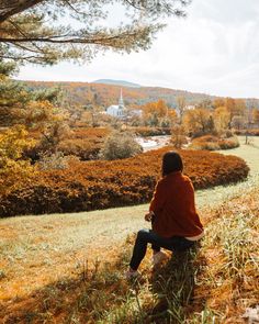 a woman sitting on top of a grass covered hillside