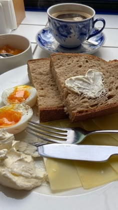 a plate with bread, eggs and butter on it next to a cup of coffee