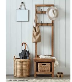 a wooden bench with an umbrella and hat hanging on the wall next to it is a wicker basket