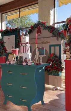 a blue dresser sitting in front of a window with christmas decorations on top of it