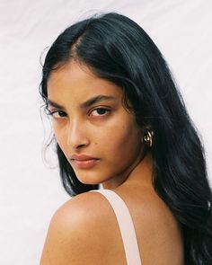 a close up of a person with long black hair and wearing a white tank top