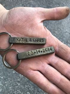 two personalized key chains are held in the palm of someone's left hand