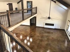 an empty living room with a ceiling fan and wooden railings on the second floor