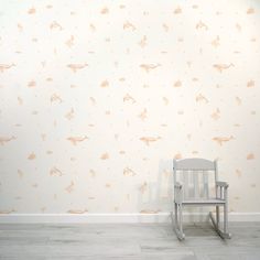 a rocking chair in front of a wall with dinosaurs on it