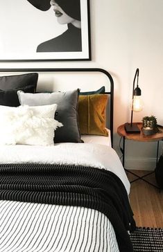 a bedroom with white walls, black and gold bedding and pictures on the wall