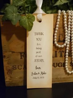 a bookmark with pearls on it sitting next to a plant in a wooden box