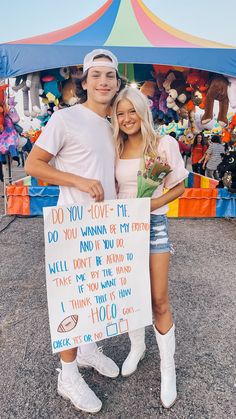 two people standing next to each other holding a sign