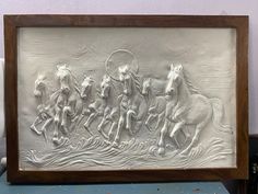 this is a sculpture of horses running in the water on a white background with wood frame