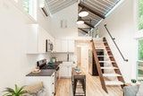 an open concept kitchen and living room with stairs leading up to the loft